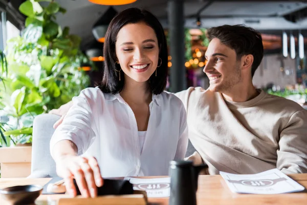 Fuoco selettivo della donna felice che prende il tovagliolo vicino all'uomo nel sushi bar — Foto stock