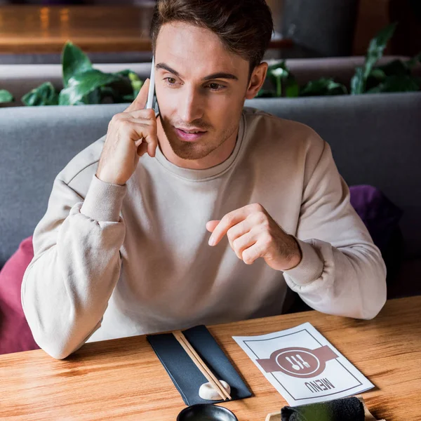 Schöner Mann, der in einer Sushi-Bar mit dem Smartphone spricht — Stockfoto