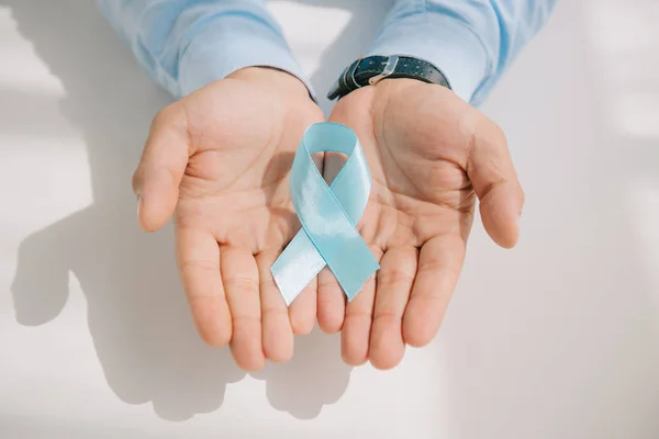 Partial view of male hands with blue awareness ribbon — Stock Photo