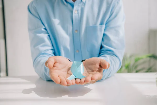 Vue recadrée de l'homme en chemise bleue tenant un ruban de sensibilisation bleu — Photo de stock