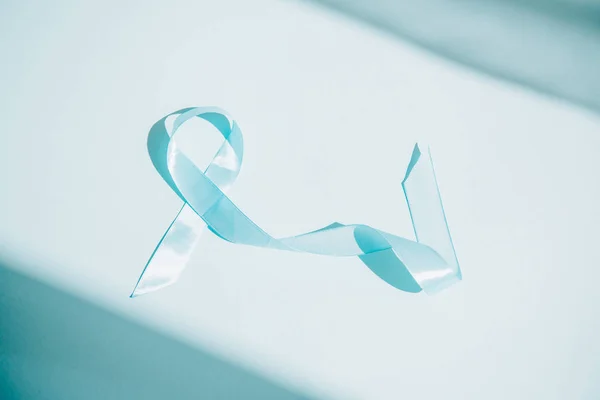 Blue awareness ribbon on white background with shadows — Stock Photo