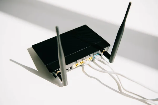 Router enchufado negro en la mesa blanca de la oficina en sol - foto de stock