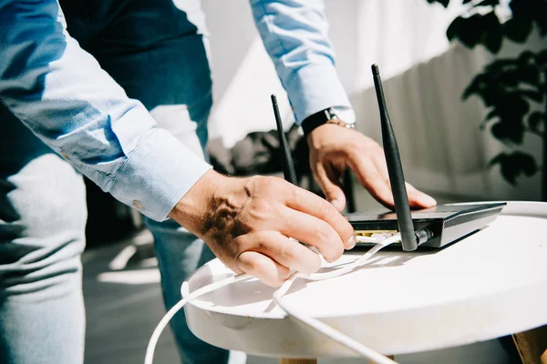 Ausgeschnittene Ansicht eines Geschäftsmannes, der Router auf weißem Tisch einsteckt — Stockfoto