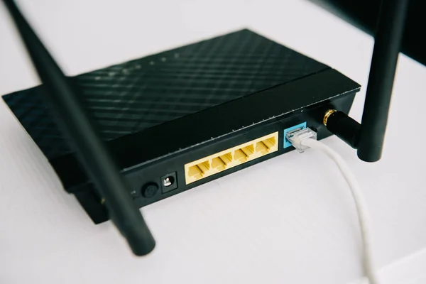 Selective focus of black plugged router on white table — Stock Photo