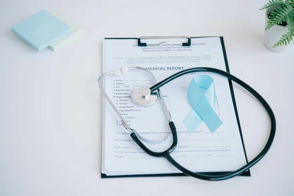 Blue awareness ribbon, medical report, stethoscope and sticky notes on white table — Stock Photo