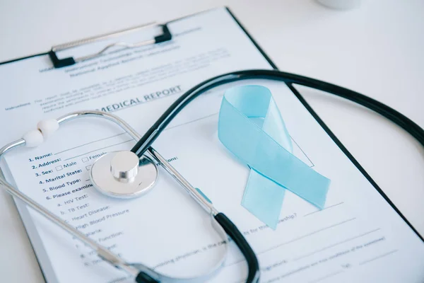 Relatório médico, estetoscópio e fita de consciência azul na mesa branca — Fotografia de Stock