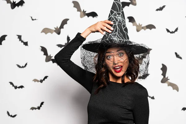 Mujer sorprendida en sombrero de bruja mirando a la cámara en Halloween - foto de stock