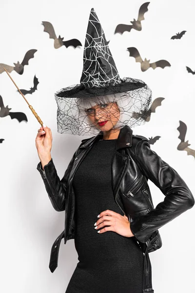 Attractive woman in witch hat and wig holding magic wand in Halloween — Stock Photo