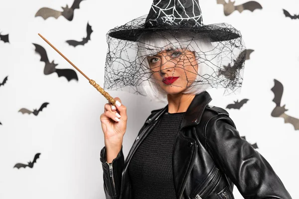 Attractive woman in witch hat and wig holding magic wand in Halloween — Stock Photo