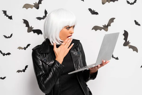 Shocked woman in white wig holding laptop in Halloween — Stock Photo