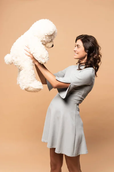 Schwangere im grauen Kleid hält Teddybär auf beigem Hintergrund — Stockfoto