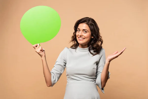 Pregnant woman in grey dress holding speech bubble on beige background — Stock Photo