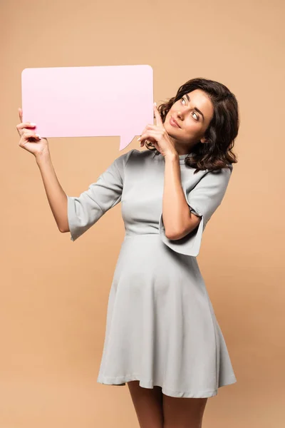 Pregnant woman in grey dress holding speech bubble on beige background — Stock Photo