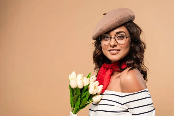 French woman in beret holding bouquet on beige background — Stock Photo