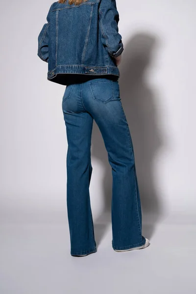 Cropped view of young woman in denim jeans and jacket standing on white — Stock Photo