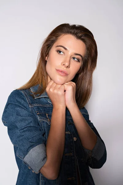 Dreamy young woman in denim jacket looking away on white — Stock Photo