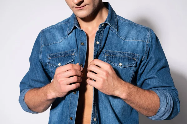 Vista recortada del hombre tocando camisa de mezclilla en blanco - foto de stock