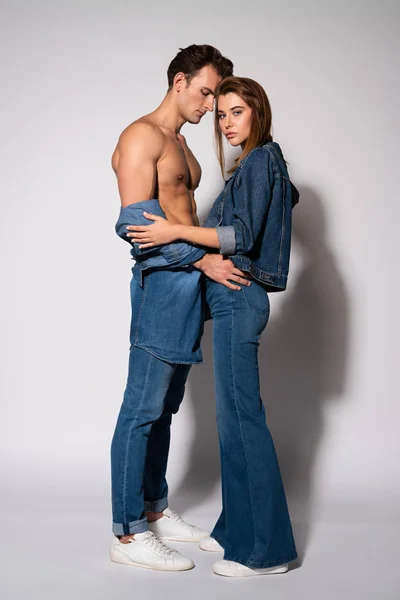 Muscular man standing with attractive young woman on white — Stock Photo