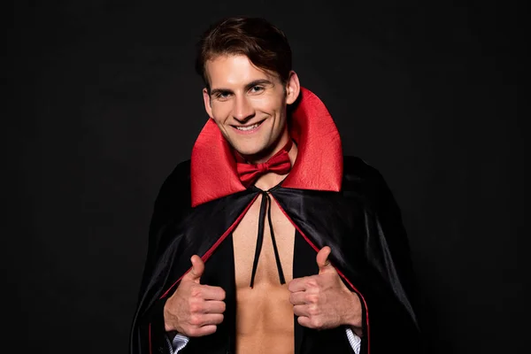 Hombre feliz en traje de Halloween vampiro mostrando pulgares hacia arriba en negro — Stock Photo