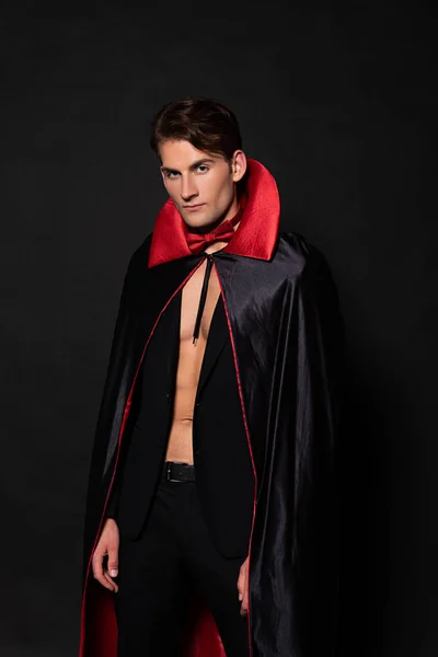 Красивий чоловік у костюмі вампіра Хеллоуїн дивиться на камеру ізольовано на чорному — стокове фото