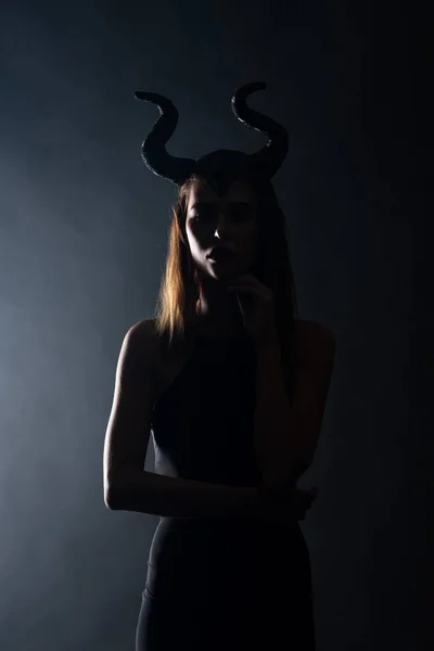 Silhouette of young woman with horns standing on black — Stock Photo