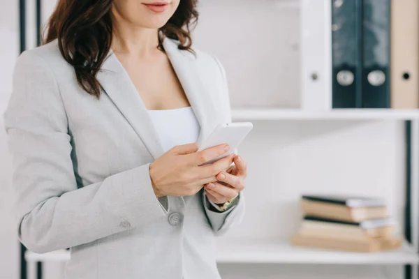 Vista parziale di elegante segretaria tramite smartphone in ufficio — Stock Photo