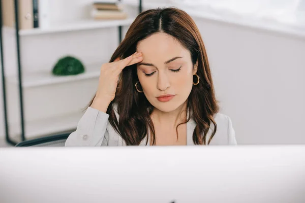 Selective focus of tired secretary suffering from headache and holding hand near head — Stock Photo