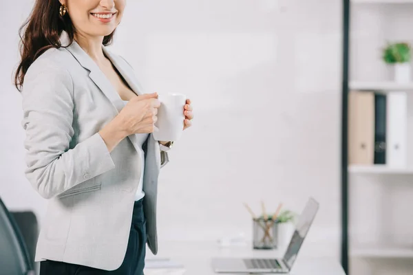 Ausgeschnittener Blick auf elegante Sekretärin mit Kaffeetasse im Büro — Stockfoto