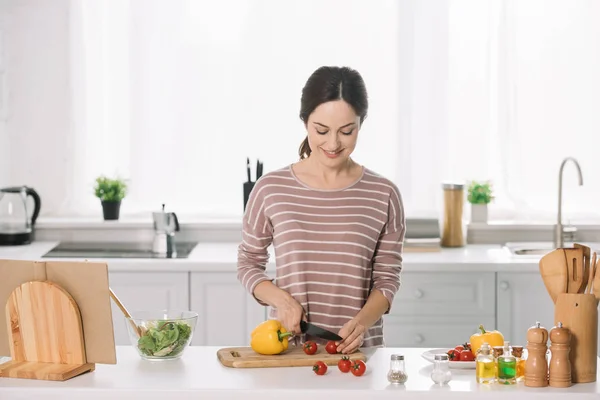 Atractiva joven corte de verduras frescas en la tabla de cortar - foto de stock