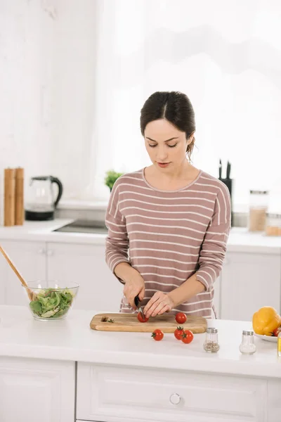 Jeune femme séduisante coupant des légumes frais sur planche à découper — Photo de stock