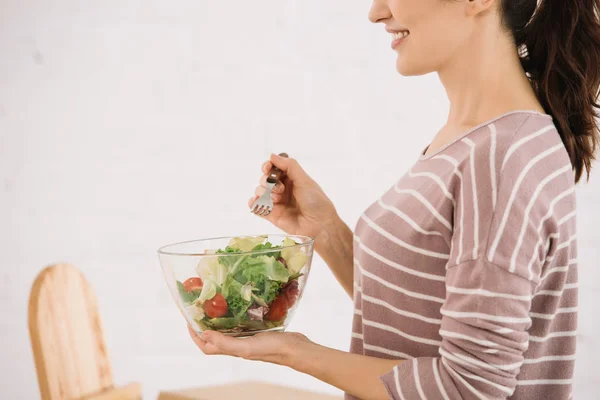 Cropped view of smiling woman holding bowl with fresh vegetable salad — Stock Photo