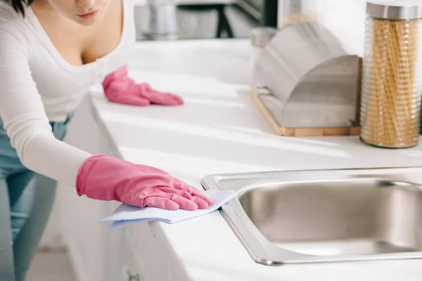 Cropped view of housewife wiping kitchen tabletop with rag — Stock Photo