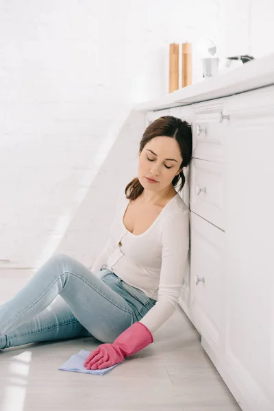 Erschöpfte Hausfrau sitzt mit geschlossenen Augen in Küche auf dem Boden — Stockfoto