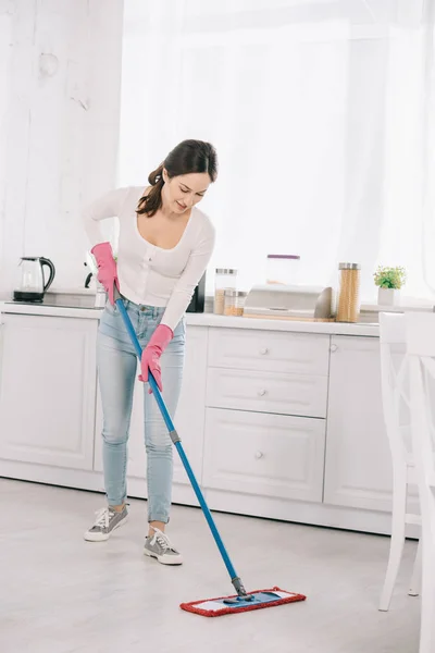 Привлекательный, молодая домохозяйка стиральный пол на кухне со шваброй — стоковое фото