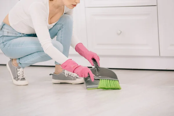 Vue recadrée de la jeune femme au foyer balayant le sol avec brosse et cuillère — Photo de stock