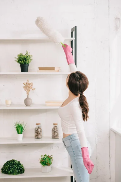 Estante de limpieza joven ama de casa con cepillo de polvo blanco - foto de stock