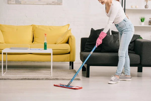 Vue recadrée du plancher de lavage femme au foyer avec serpillière près des canapés jaunes et gris — Photo de stock