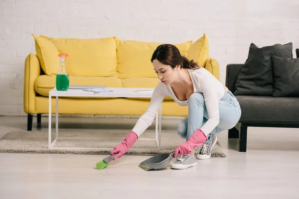 Attractive housewife sweeping floor with brush and scoop — Stock Photo