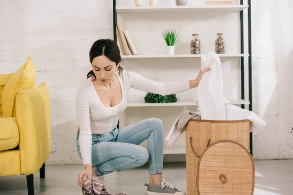 Joven ama de casa tomando ropa de la cesta de la ropa - foto de stock