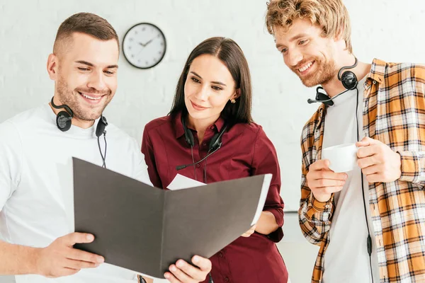 Broker felici guardando la cartella e sorridendo in call center — Foto stock