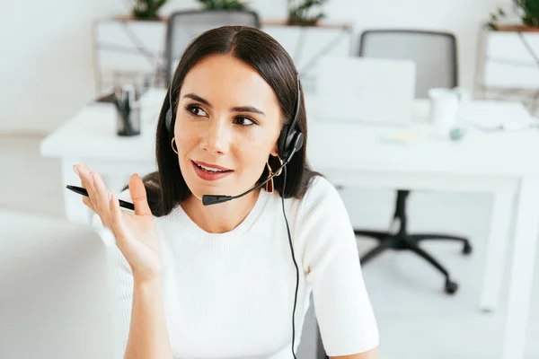 Selective focus of attractive broker looking away while holding pen in call center — Stock Photo