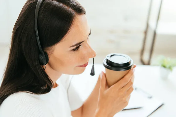 Overhead view of broker in headset holding paper cup in office — Stock Photo