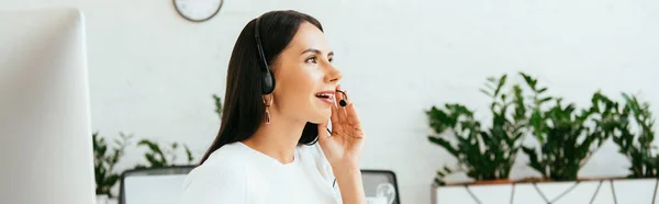 Panoramic shot of smiling broker in headset talking in office — Stock Photo