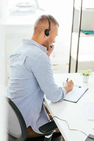 Felice broker in auricolare penna vicino appunti — Foto stock