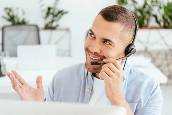 Messa a fuoco selettiva di operatore felice e bello in agenzia broker toccare auricolare — Foto stock