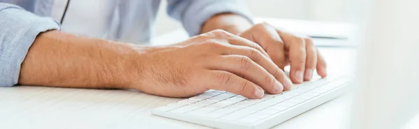 Plano panorámico del hombre escribiendo en el teclado de la computadora - foto de stock