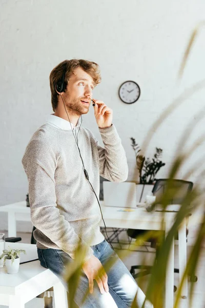 Enfoque selectivo del operador barbudo en corredores agencia tocando auriculares - foto de stock