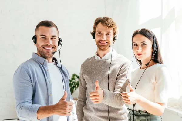 Corredores felices en auriculares que muestran los pulgares hacia arriba - foto de stock