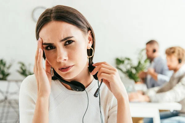 Tired broker with headache near coworkers in office — Stock Photo