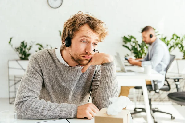 Upset broker in headset near tissue box in office — Stock Photo